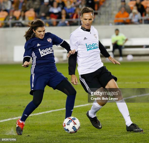 Mia Hamm attempts to hold off Steve Nash as she brings the ball up the field during the Kick In For Houston Charity Soccer Match at BBVA Compass...
