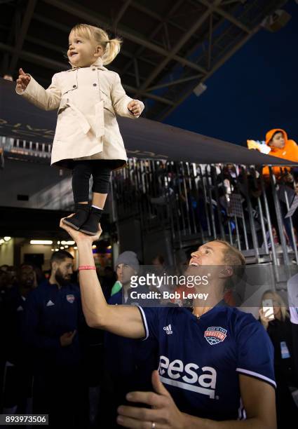 Stuart Holden holds up his daughter Kennady as Steve Nash looks on before the start of the Kick In For Houston Charity Soccer Match at BBVA Compass...