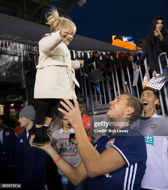 Stuart Holden holds up his daughter Kennady as Steve Nash looks on before the start of the Kick In For Houston Charity Soccer Match at BBVA Compass...