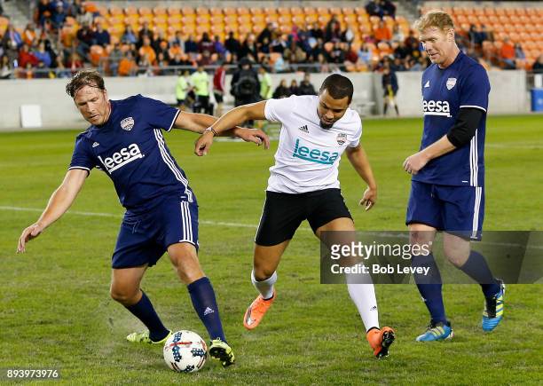 Bode Miller holds off Charlie Davies as Alexi Lalas looks on during the Kick In For Houston Charity Soccer Match at BBVA Compass Stadium on December...