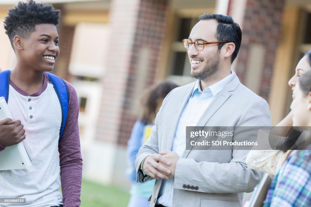 Hispanic male teacher visits with students before class