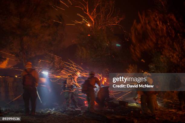 Strong wind blows embers around inmate firefighters putting out hot spots at the Thomas Fire on December 16, 2017 in Montecito, California. The...