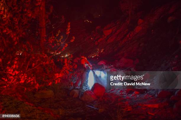 The lights of a firetruck illuminate a firefighter dowsing a hot spot at the Thomas Fire on December 16, 2017 in Montecito, California. The National...
