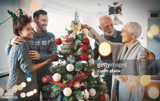 family decorating a christmas tree. - family decorating stock pictures, royalty-free photos & images