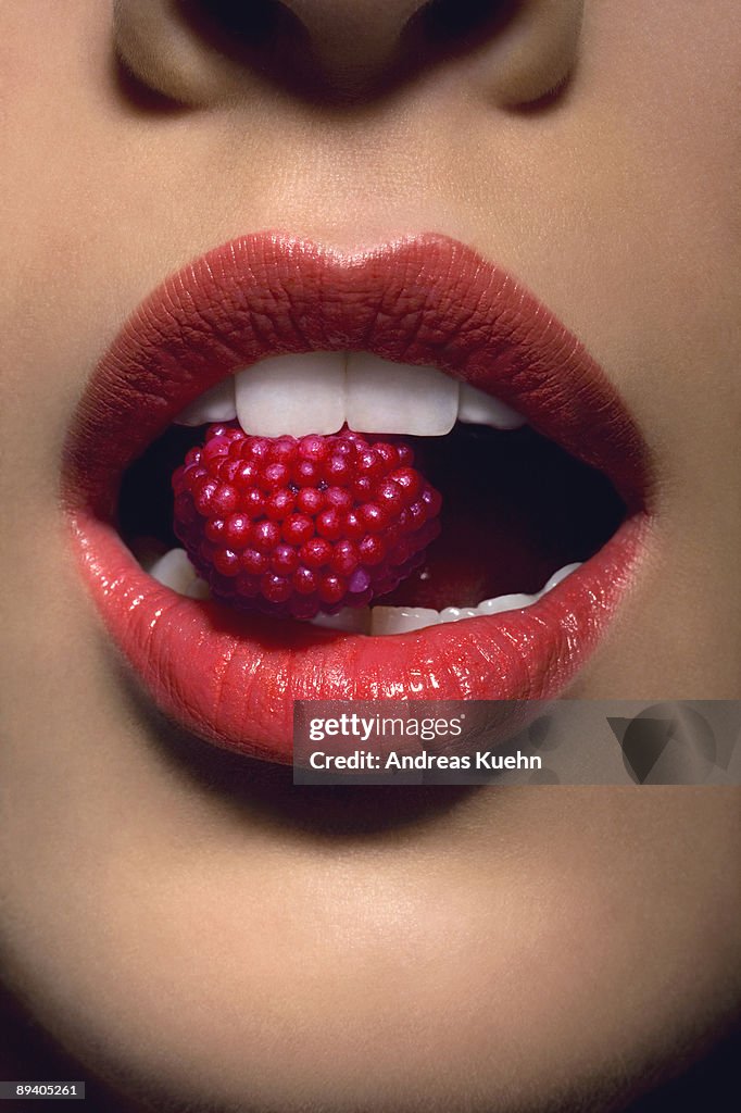 Young woman with candy between teeth, close up.