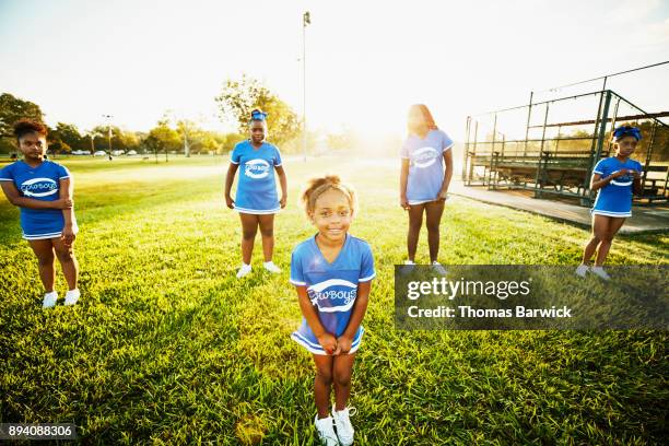 smiling young cheerleader lined up with teammate for early morning practice in park - black cheerleaders stock pictures, royalty-free photos & images