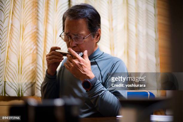 japanese senior men blowing harmonica while taking a break in work in okinawa - harmonica stock pictures, royalty-free photos & images