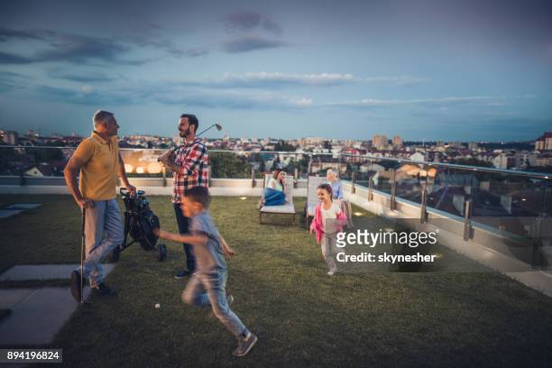 multi-generation family spending evening time on a penthouse balcony. - penthouse girl stock pictures, royalty-free photos & images