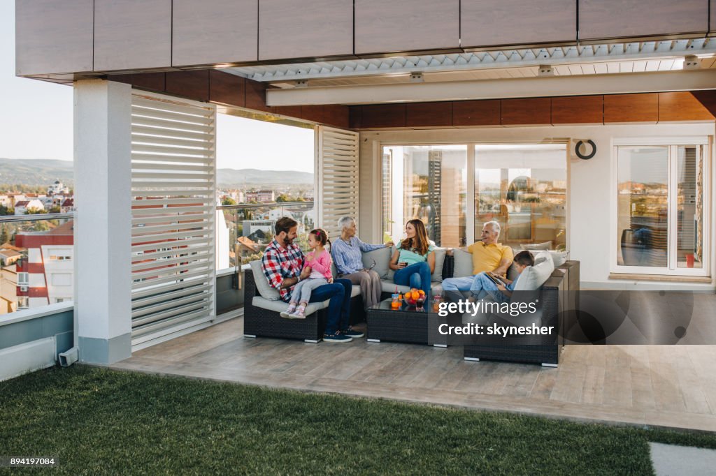 Happy multi-generation family talking while relaxing on a penthouse patio.