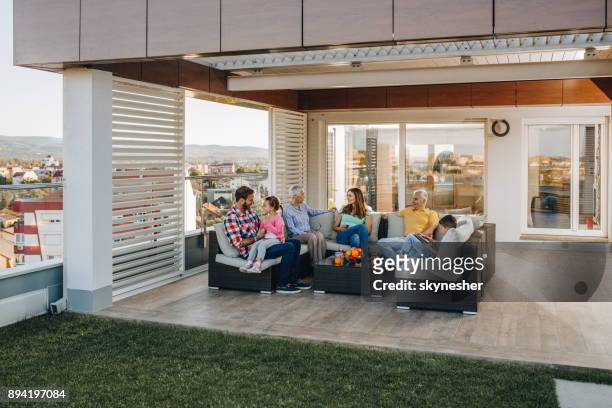 família de várias gerações feliz falando enquanto relaxa em um pátio de cobertura. - women of penthouse - fotografias e filmes do acervo