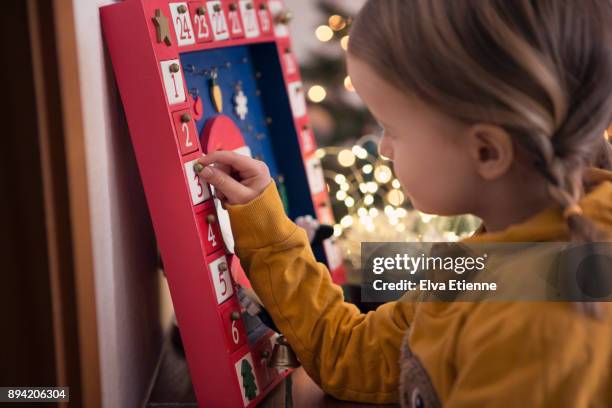 girl (4-5) opening christmas advent calendar - christmas calendar stock-fotos und bilder