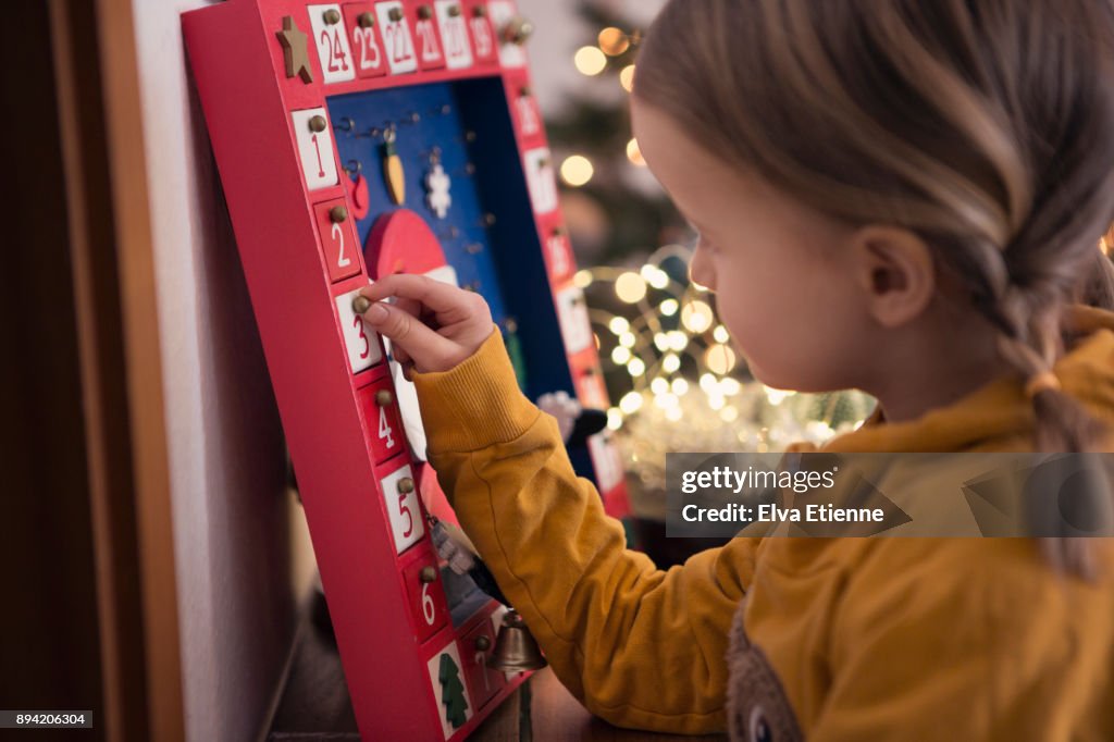 Girl (4-5) opening Christmas advent calendar