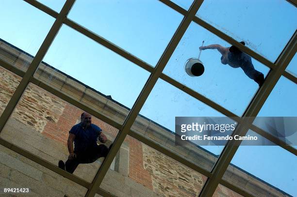 March 2006. El Escorial. Madrid . Workers cleaning a roof of glass.