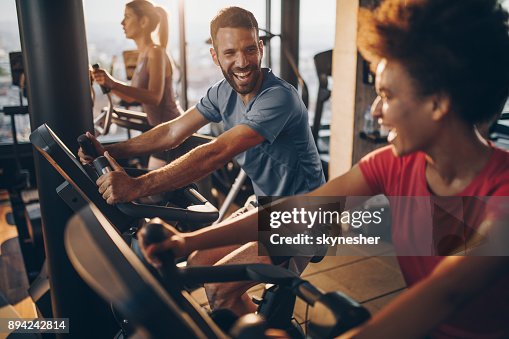 Fröhliche männlichen Athleten im Gespräch mit seinem Freund auf spinning Training in einem Fitnessstudio. Fröhliche männlichen Athleten im Gespräch mit seinem Freund auf spinning Training in einem Fitnessstudio.