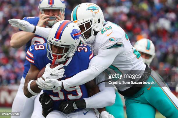 Travaris Cadet of the Buffalo Bills runs the ball as Reshad Jones of the Miami Dolphins attempts to tackle him during the first quarter on December...