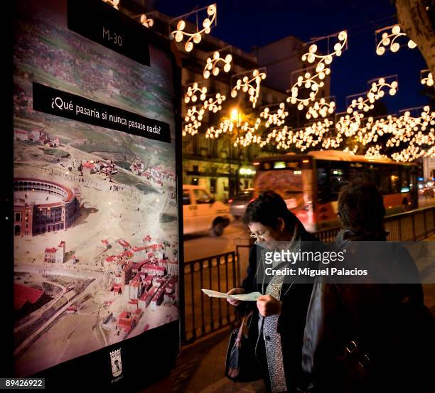 Madrid In the image, a tourist consults a map and of fund the Christmas lighting of the Street Alcala.