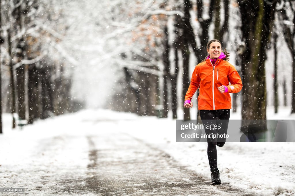 Winter Breaks - 40 years old woman running on country road through alley on cold winter day with snow and frost