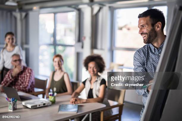 happy business leader presenting his team a new business plan on whiteboard. - small group of people stock pictures, royalty-free photos & images