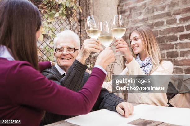 social seniors. two granddaughters and grandfather celebrating, toasting with white vine - white vinegar stock pictures, royalty-free photos & images