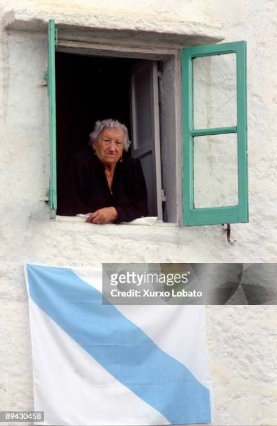 Galicia. Elderly woman appears to a window. Under the window there is a Galicia´s flag.