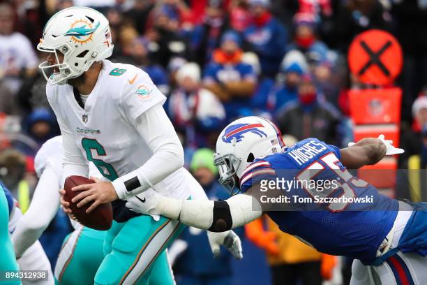 Jay Cutler of the Miami Dolphins holds the ball as Jerry Hughes of the Buffalo Bills attempts to tackle him during the first quarter on December 17,...