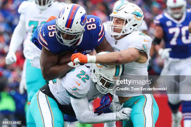 Charles Clay of the Buffalo Bills runs with the ball as T.J. McDonald of the Miami Dolphins and teammate Kiko Alonso attempt to tackle Clay during...