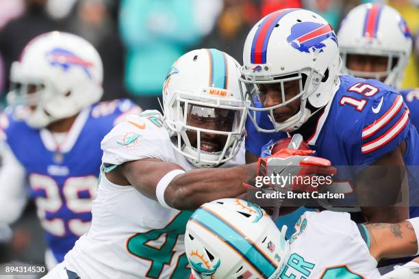 Brandon Tate of the Buffalo Bills holds the ball as Alterraun Verner of the Miami Dolphins and teammate Torry McTyer attempt to tackle Tate during...