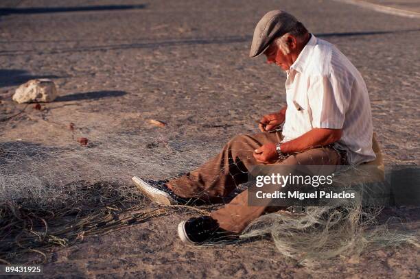 Fisherman sewing nets.