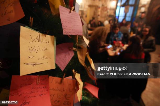 Picture taken on December 17, 2017 shows New Year wishes written on cards hanging on a Christmas tree in a coffee shop in the Syrian capital...