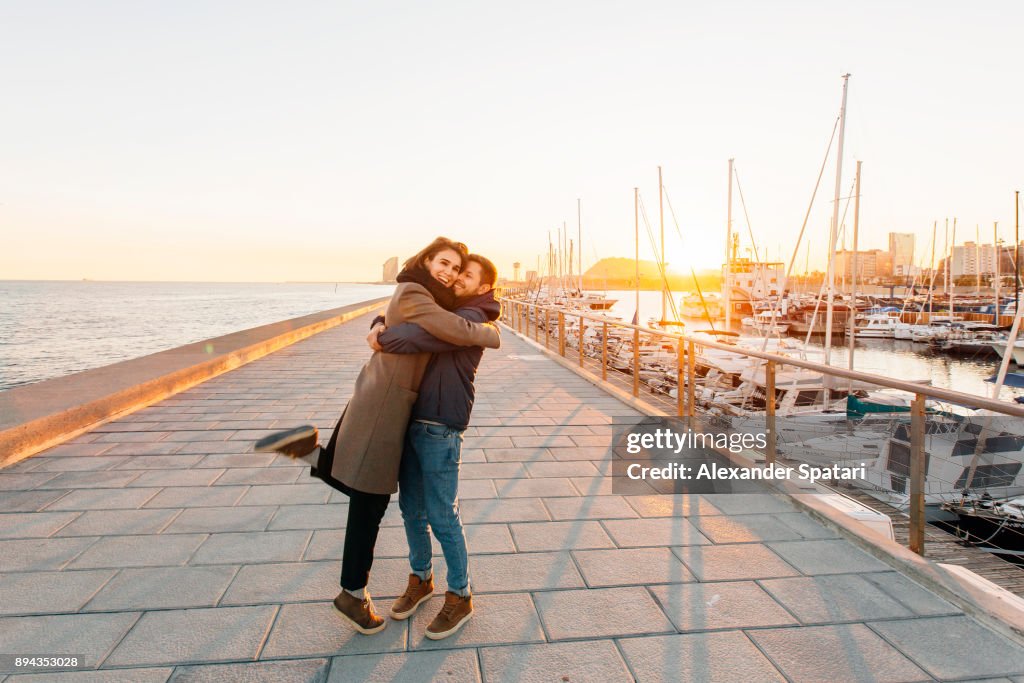 Young happy couple hugging each other at the pier in Barcelona, Spain