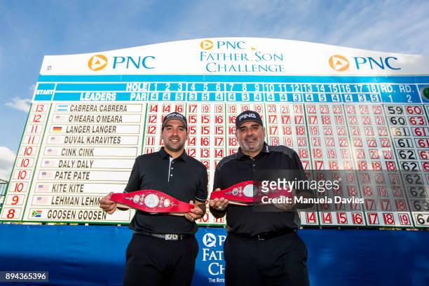 Angel Cabrera and Angel Cabrera Jr. Of Argentina celebrate with the winners' trophies in front of the score board after the final round of the PNC...