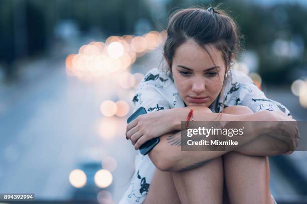 donna depressa seduta sul parapetto del ponte - malumore foto e immagini stock