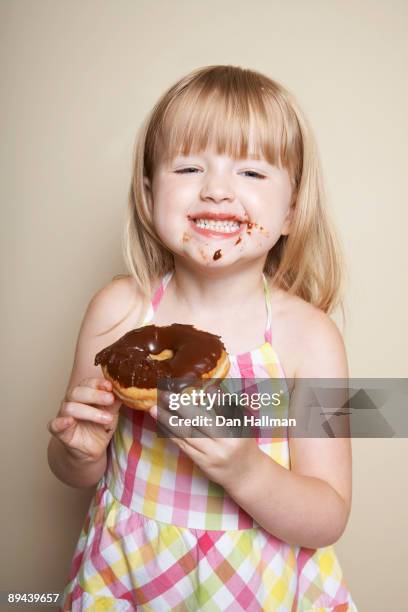 four year old girl enjoying chocolate donut. - chocoladedonut stockfoto's en -beelden