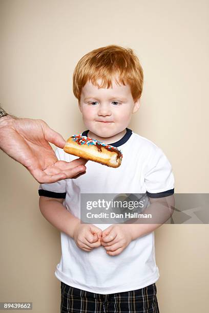 three year old boy being tempted by donut. - chocoladedonut stockfoto's en -beelden