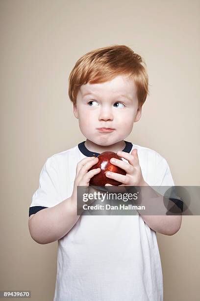 boy, 3 years old, holding an apple. - chubby boy fotografías e imágenes de stock