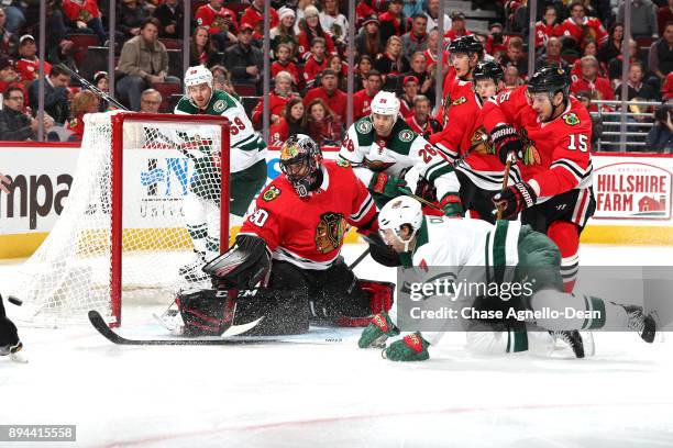 Goalie Corey Crawford of the Chicago Blackhawks guards the net, as Zack Mitchell and Daniel Winnik of the Minnesota Wild watch, and Artem Anisimov of...