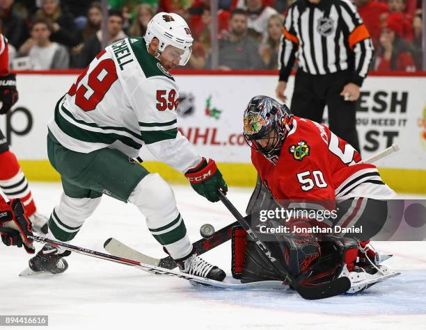 Corey Crawford of the Chicago Blackhawks makes a save against Zack Mitchell of the Minnesota Wild at the United Center on December 17, 2017 in...