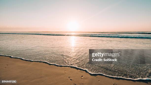 sonnenaufgang über den wellen - sunrise beach stock-fotos und bilder