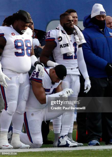 Damon Harrison and Landon Collins of the New York Giants rest their hands on teammate Olivier Vernon as Vernon kneels during the national anthem...
