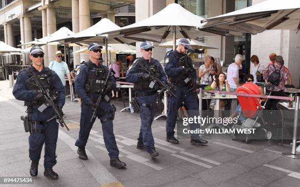 Members of the New South Wales state riot squad police carry machine guns as they patrol on Sydney's Circular Quay on December 18, 2017....