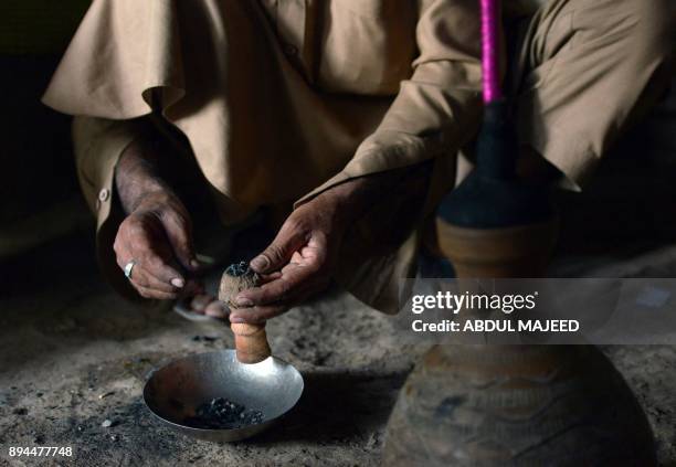 This picture taken on October 25, 2017 shows a Pakistani smoker putting hashish into a chillum pipe before smoking in Peshawar. In conservative...