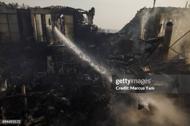 Humboldt County firefighter Jimmy McHaffie, right, sprays down smoldering fire underneath the rubble of a home that was destroyed by the Thomas Fire,...