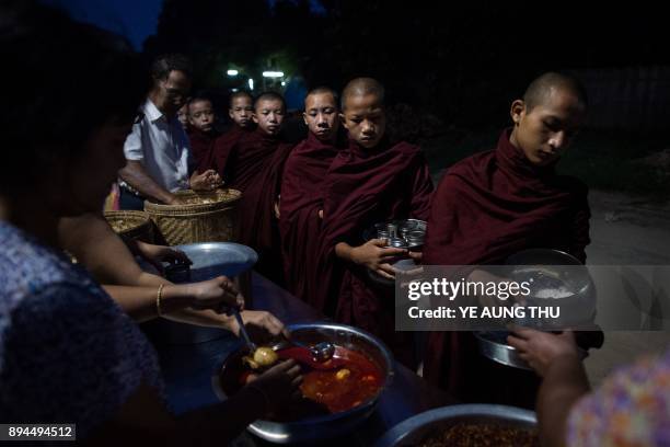 In this photo taken on May 25 Buddhist monk novices collect daily alms from devotees seeking to make merit in the pre-dawn hours in Bagan. Buddhist...