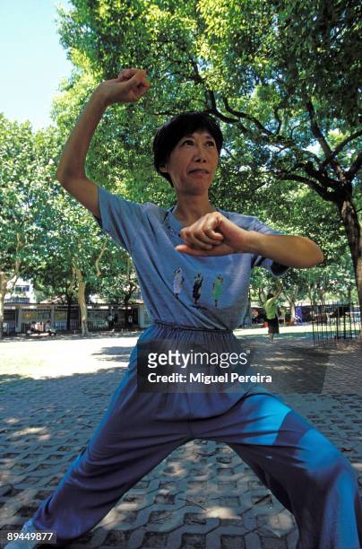 Woman does Tai Chi Chuan, in a park in Shanghai. Tai Chi is a martial art that is popular throughout the world.