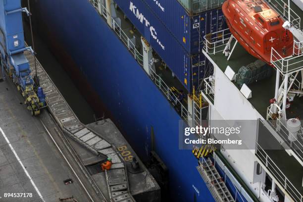 Worker rests next to the Cosco New York container ship at the Jawaharlal Nehru Port, operated by Jawaharlal Nehru Port Trust , in Navi Mumbai,...