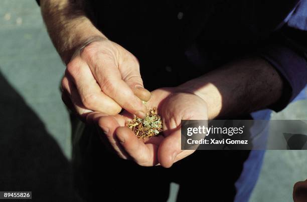 Man preparing a joint A drug consumer mixes in his hands hashish and tobacco to manufacture a joint