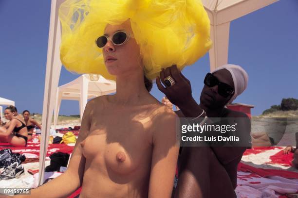 Happening in the beach. Ibiza Island A man places an attractive yellow turban to a naked young woman.