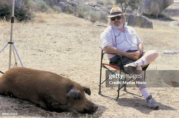 Jose Luis Cuerda, cine productor Sat beside a pig in the shooting set of 'La Marrana'