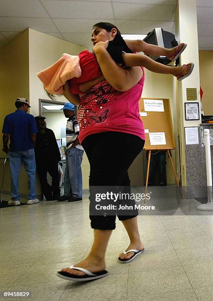 Nicole Murphy carries her daughter Reyna inside the lobby of the Stout Street Clinic on July 29, 2009 in Denver, Colorado. The clinic, operated by...