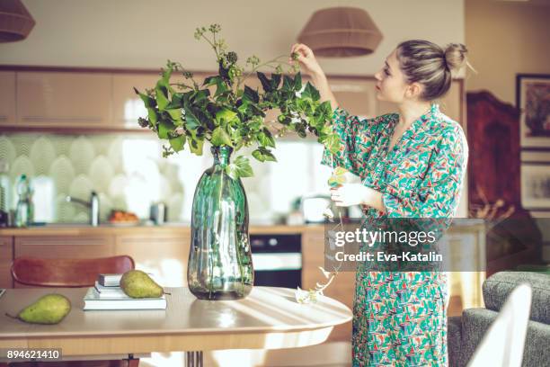 junge frau zu hause - blumenvase stock-fotos und bilder